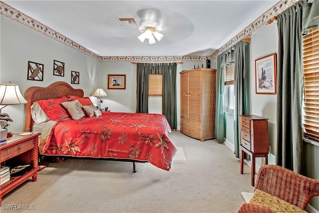 bedroom with visible vents, light colored carpet, and ceiling fan