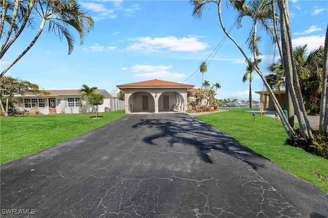 mediterranean / spanish-style home with a front lawn, driveway, and stucco siding