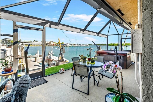 view of patio / terrace featuring a water view, a hot tub, and glass enclosure