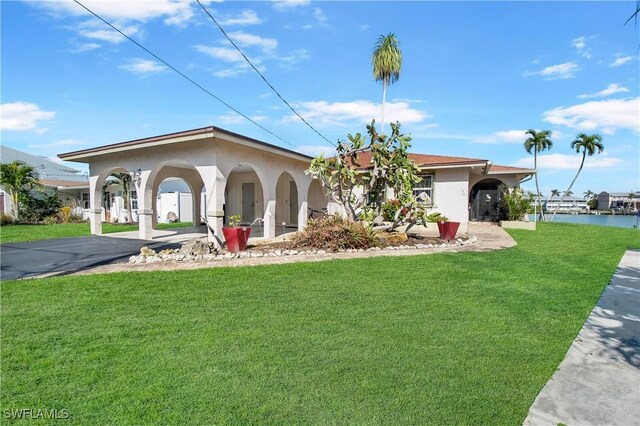 mediterranean / spanish-style home featuring a front yard, a water view, and a carport