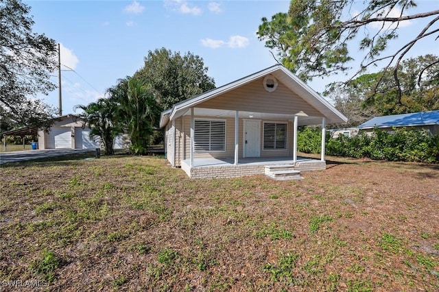 rear view of house with a garage, a porch, and a yard