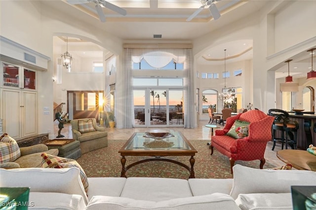 living room with ceiling fan with notable chandelier, a towering ceiling, and coffered ceiling