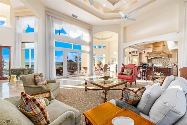 living room featuring ceiling fan, crown molding, and a towering ceiling