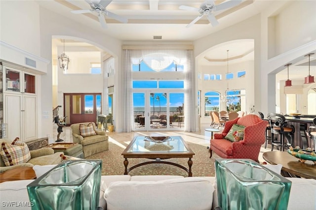 living room featuring ceiling fan with notable chandelier and a high ceiling