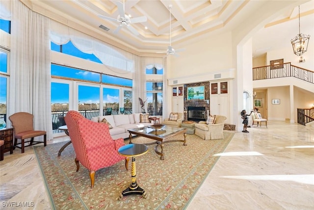 living room featuring ceiling fan with notable chandelier, a high ceiling, ornamental molding, and coffered ceiling