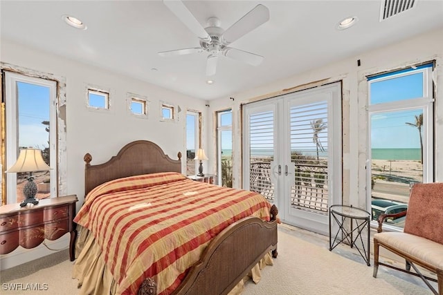 bedroom featuring a water view, access to exterior, light carpet, and ceiling fan