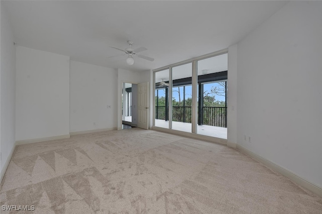 carpeted empty room with expansive windows and ceiling fan