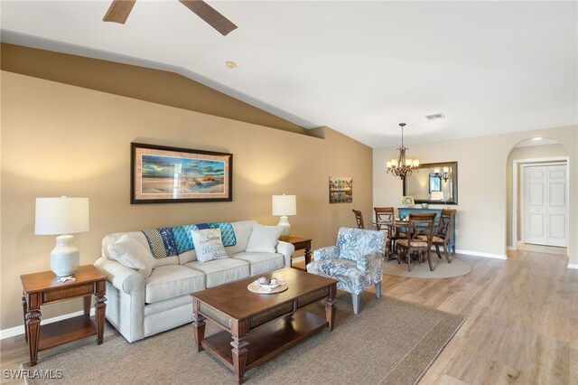 living room with light hardwood / wood-style floors, ceiling fan with notable chandelier, and lofted ceiling