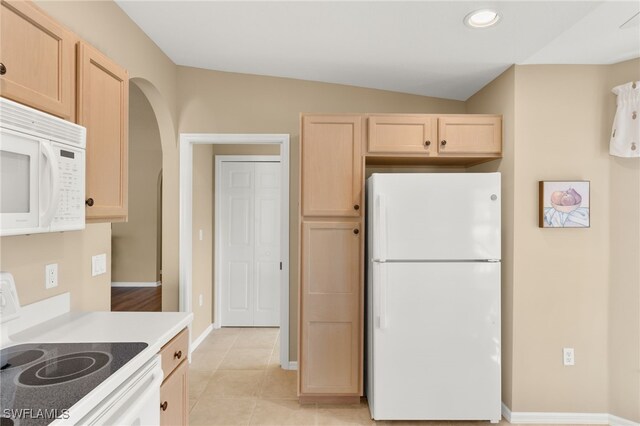 kitchen featuring light brown cabinetry, white appliances, light tile patterned floors, and lofted ceiling