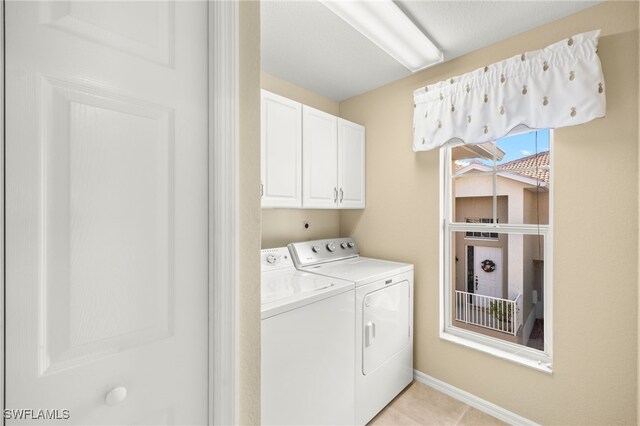 laundry area with light tile patterned flooring, cabinets, and independent washer and dryer