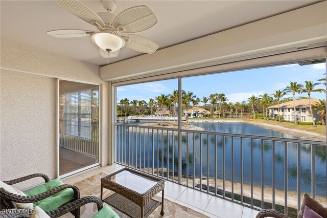 sunroom / solarium featuring ceiling fan and a water view