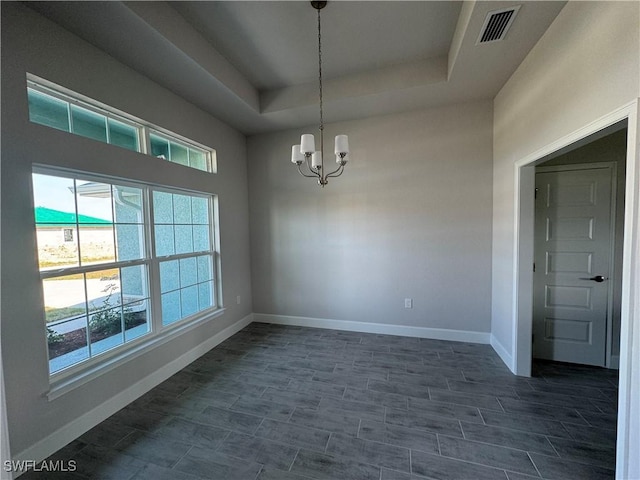 spare room with an inviting chandelier, baseboards, visible vents, and a raised ceiling