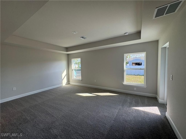 spare room with a tray ceiling, visible vents, plenty of natural light, and baseboards