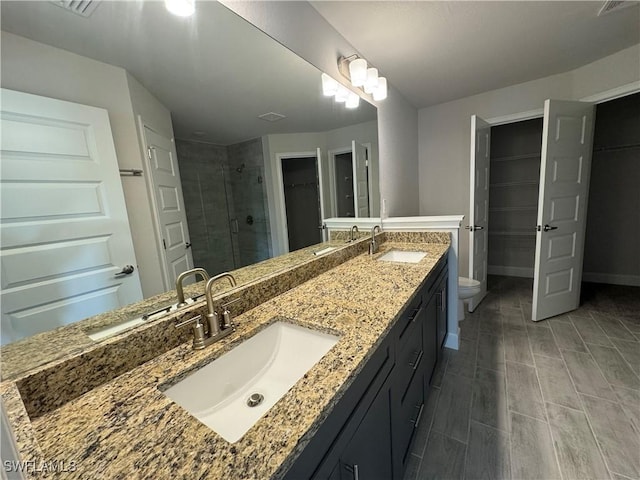 full bathroom with toilet, a shower stall, a spacious closet, and a sink