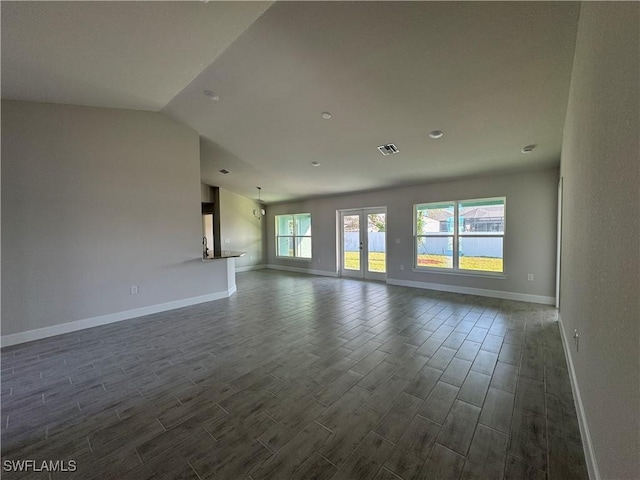 unfurnished living room featuring vaulted ceiling, dark wood-style flooring, and baseboards