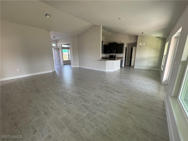 unfurnished living room featuring baseboards, visible vents, vaulted ceiling, and wood finish floors