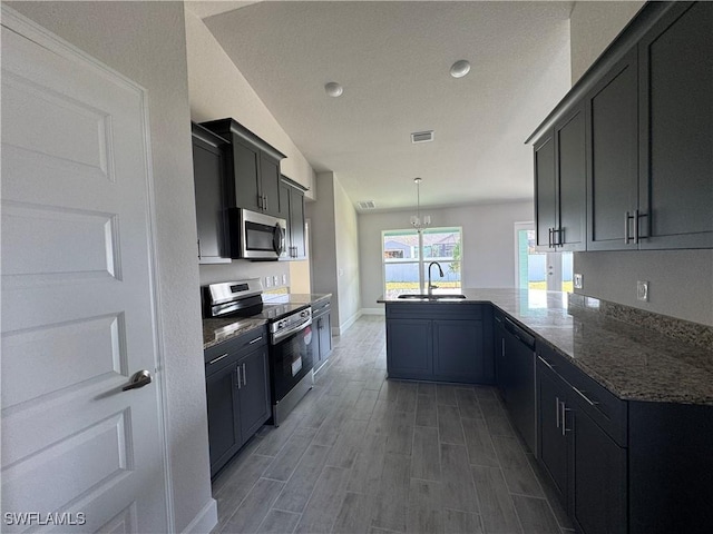 kitchen featuring visible vents, dark stone counters, a peninsula, stainless steel appliances, and pendant lighting