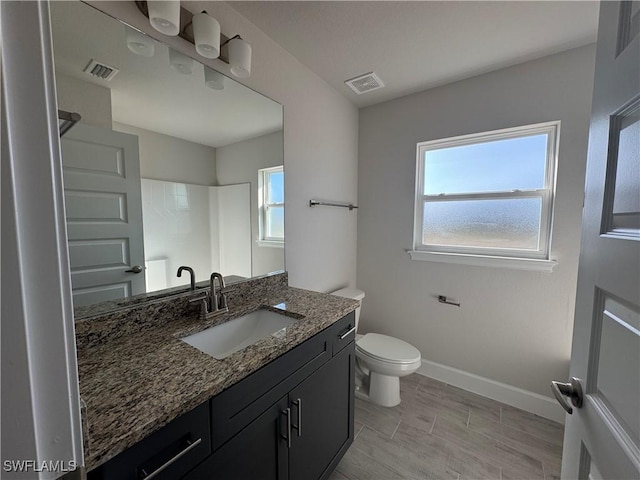 full bath with a wealth of natural light, visible vents, vanity, and baseboards