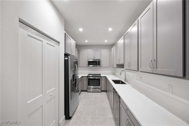 kitchen with appliances with stainless steel finishes, gray cabinets, and sink