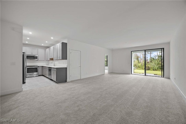 unfurnished living room featuring sink and light carpet