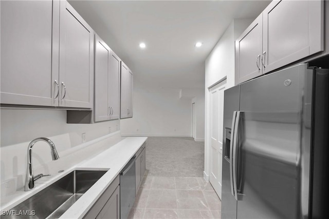 kitchen featuring stainless steel appliances, light colored carpet, gray cabinets, and sink