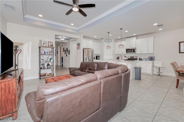 living room with ceiling fan, crown molding, and a tray ceiling