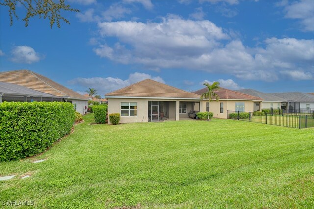 back of house featuring a lawn and a sunroom