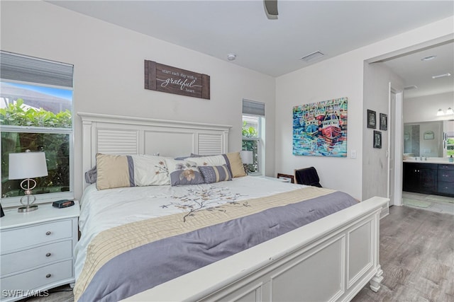 bedroom with light wood-type flooring, connected bathroom, and ceiling fan