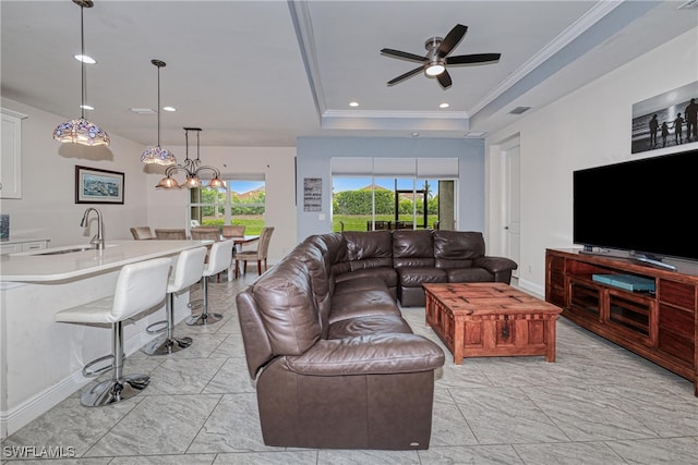 living room with sink, a wealth of natural light, a tray ceiling, and crown molding