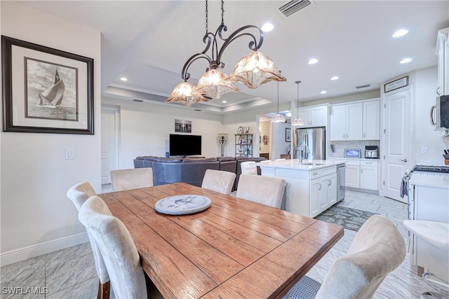 dining space featuring sink, a notable chandelier, and a tray ceiling