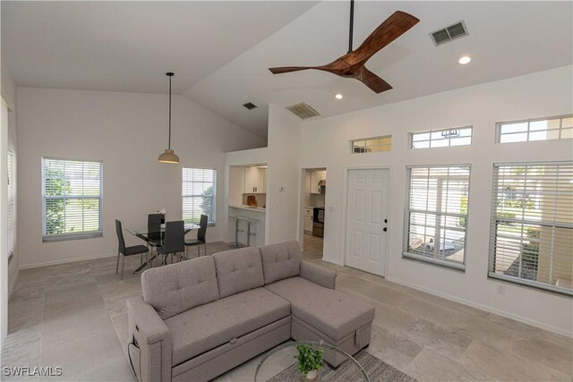 living area with baseboards, high vaulted ceiling, visible vents, and a ceiling fan