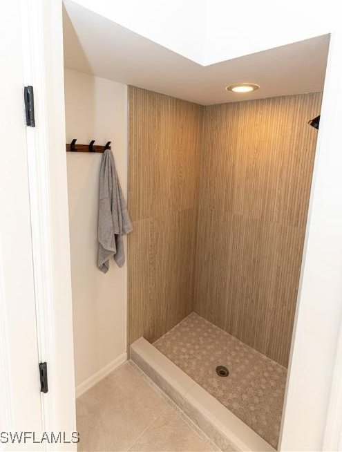 full bathroom with tile patterned flooring, baseboards, and tiled shower