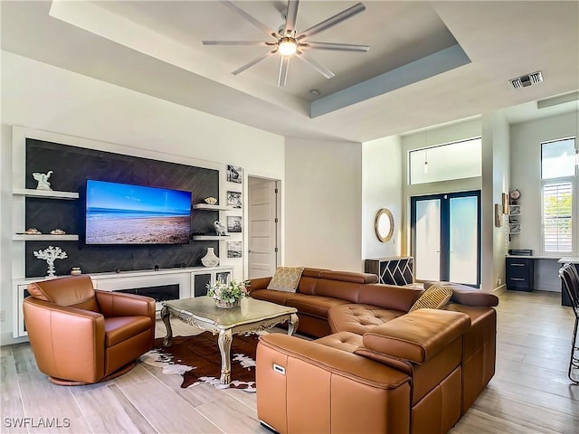 living room with ceiling fan, french doors, built in shelves, and a tray ceiling