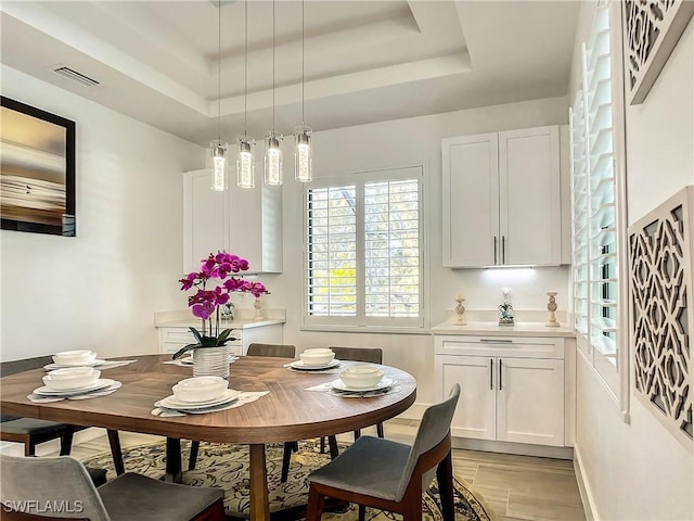 dining space featuring a raised ceiling and light hardwood / wood-style flooring