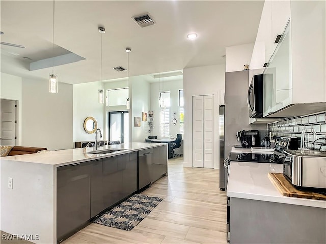 kitchen featuring decorative light fixtures, stainless steel appliances, white cabinetry, ceiling fan, and sink