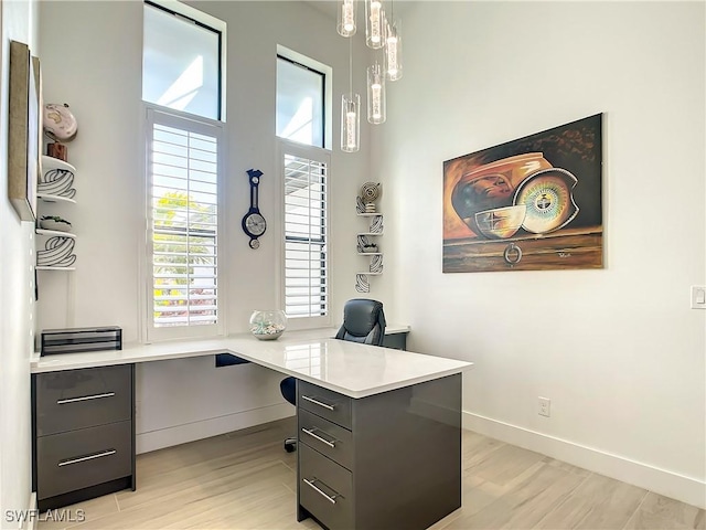 home office with light wood-type flooring and built in desk