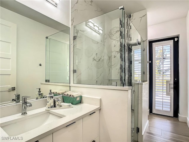 bathroom featuring a shower with door and vanity