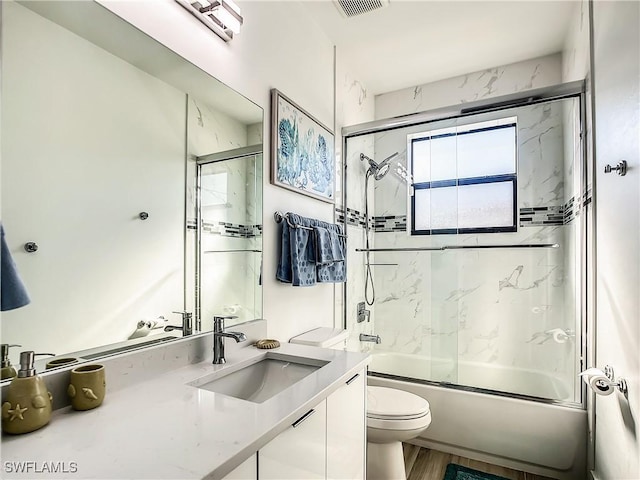 full bathroom with toilet, wood-type flooring, vanity, and bath / shower combo with glass door