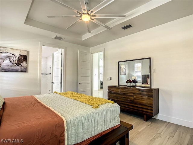 bedroom featuring ceiling fan, a raised ceiling, and ensuite bath