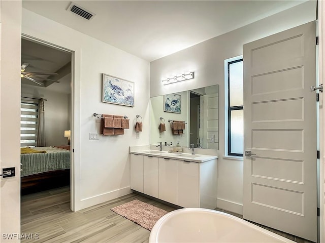 bathroom featuring ceiling fan, a tub to relax in, vanity, and wood-type flooring