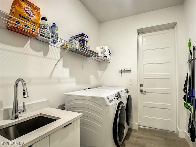 laundry area with sink, separate washer and dryer, and light hardwood / wood-style flooring