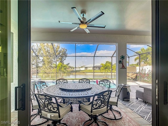 sunroom featuring ceiling fan and a water view