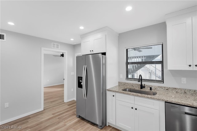 kitchen featuring white cabinetry, ceiling fan, appliances with stainless steel finishes, light stone counters, and sink