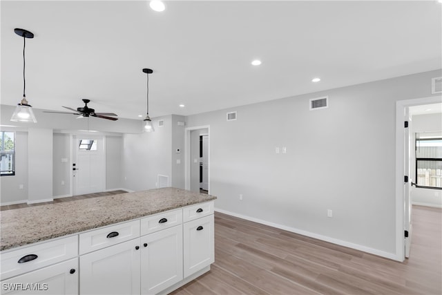 kitchen with ceiling fan, light stone countertops, hanging light fixtures, and white cabinetry