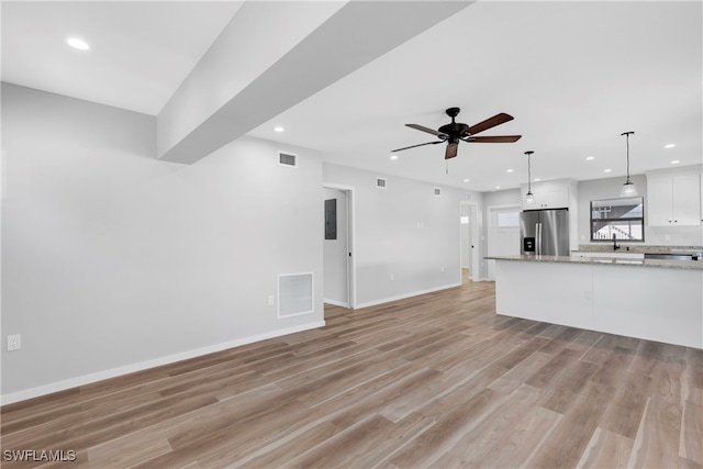 unfurnished living room with ceiling fan, light wood-type flooring, and sink