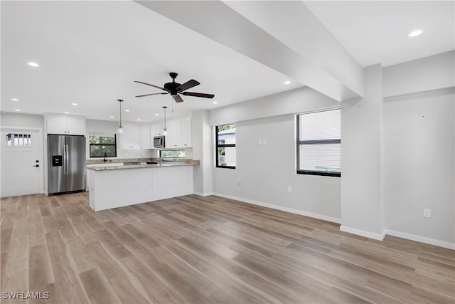 kitchen with white cabinetry, kitchen peninsula, stainless steel appliances, pendant lighting, and light hardwood / wood-style flooring