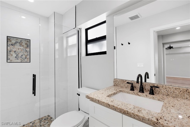 bathroom featuring ceiling fan, toilet, vanity, and walk in shower