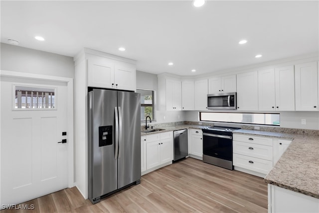 kitchen with white cabinets, appliances with stainless steel finishes, sink, and light hardwood / wood-style flooring