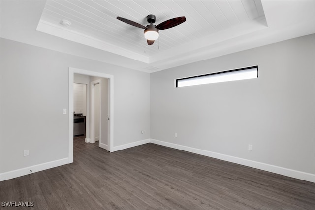 empty room featuring dark wood-type flooring, ceiling fan, and a raised ceiling