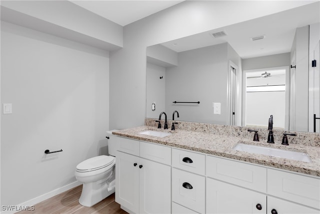 bathroom with toilet, vanity, and wood-type flooring